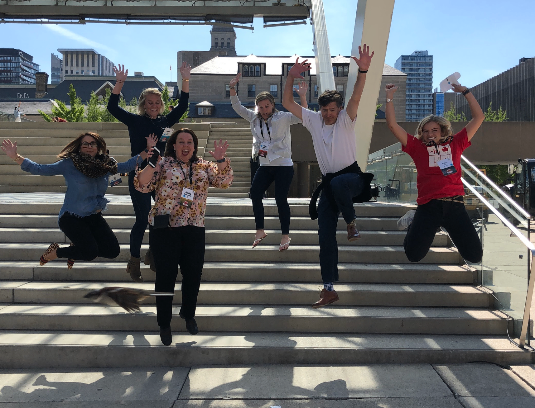 Team of colleagues gathered around a phone solving a challenge on a city sidewalk.